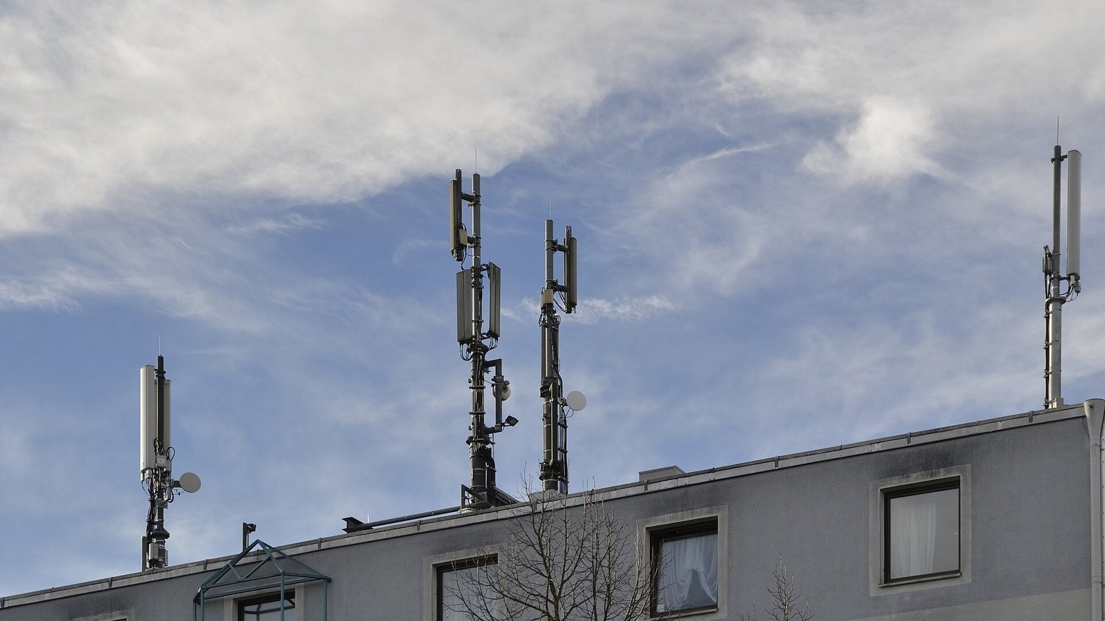 Moderner Mobilfunkmast in einer Stadt mit Smartphone im Vordergrund für schnelles 5G-Internet