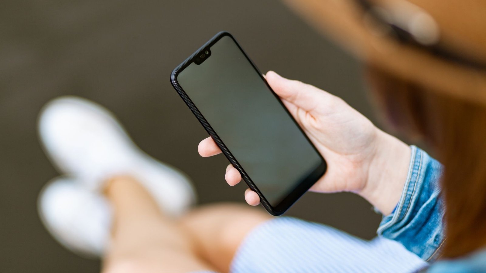 Person hält ein modernes Smartphone in einer schützenden Bumper-Hülle in den Händen